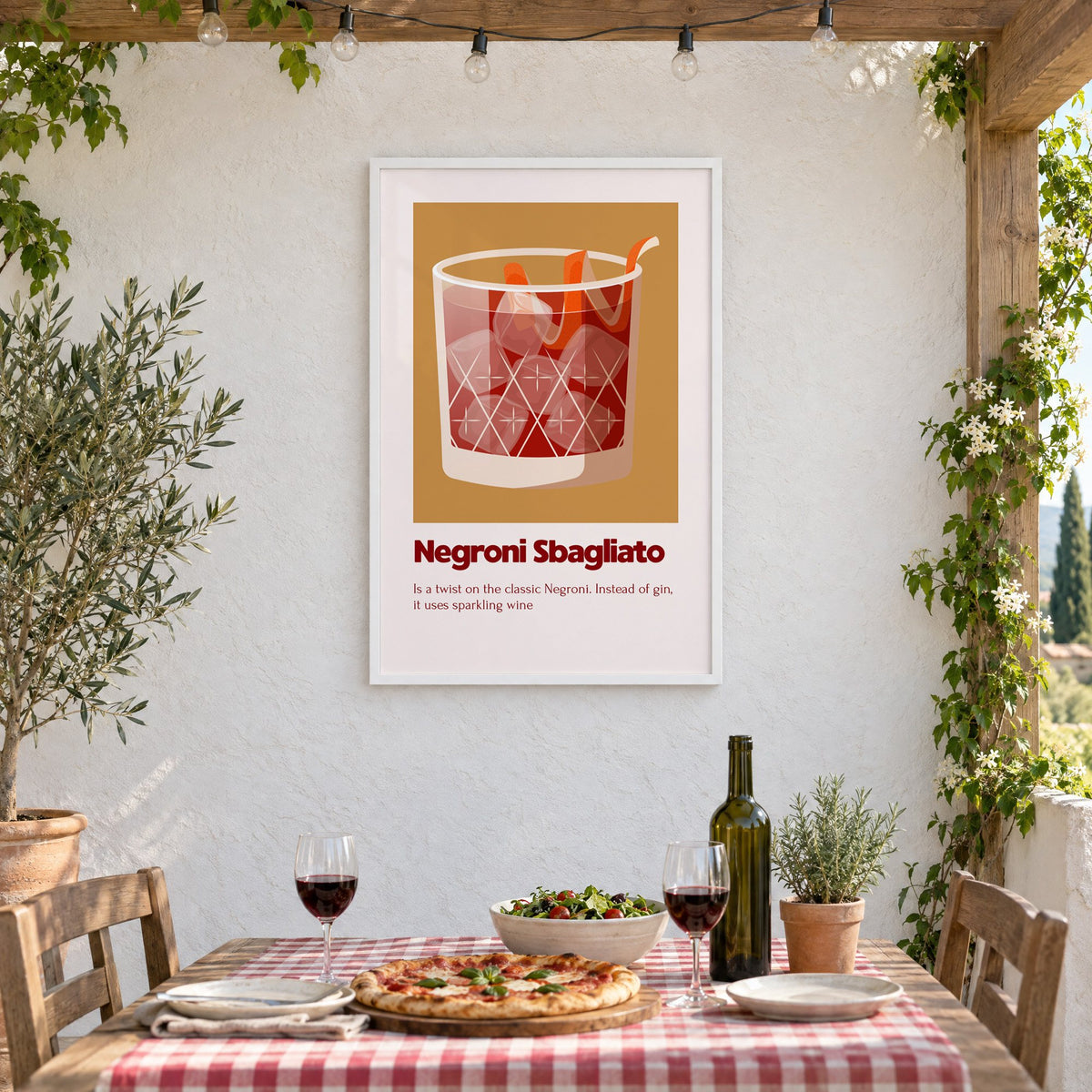 Negroni Sbagliato rocks glass ochre card print in a white frame on a stucco wall above a checked-cloth table with pizza and red wine