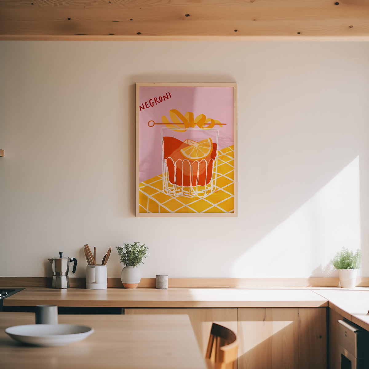 Negroni print in an oak frame above a wood counter with a moka pot and herbs