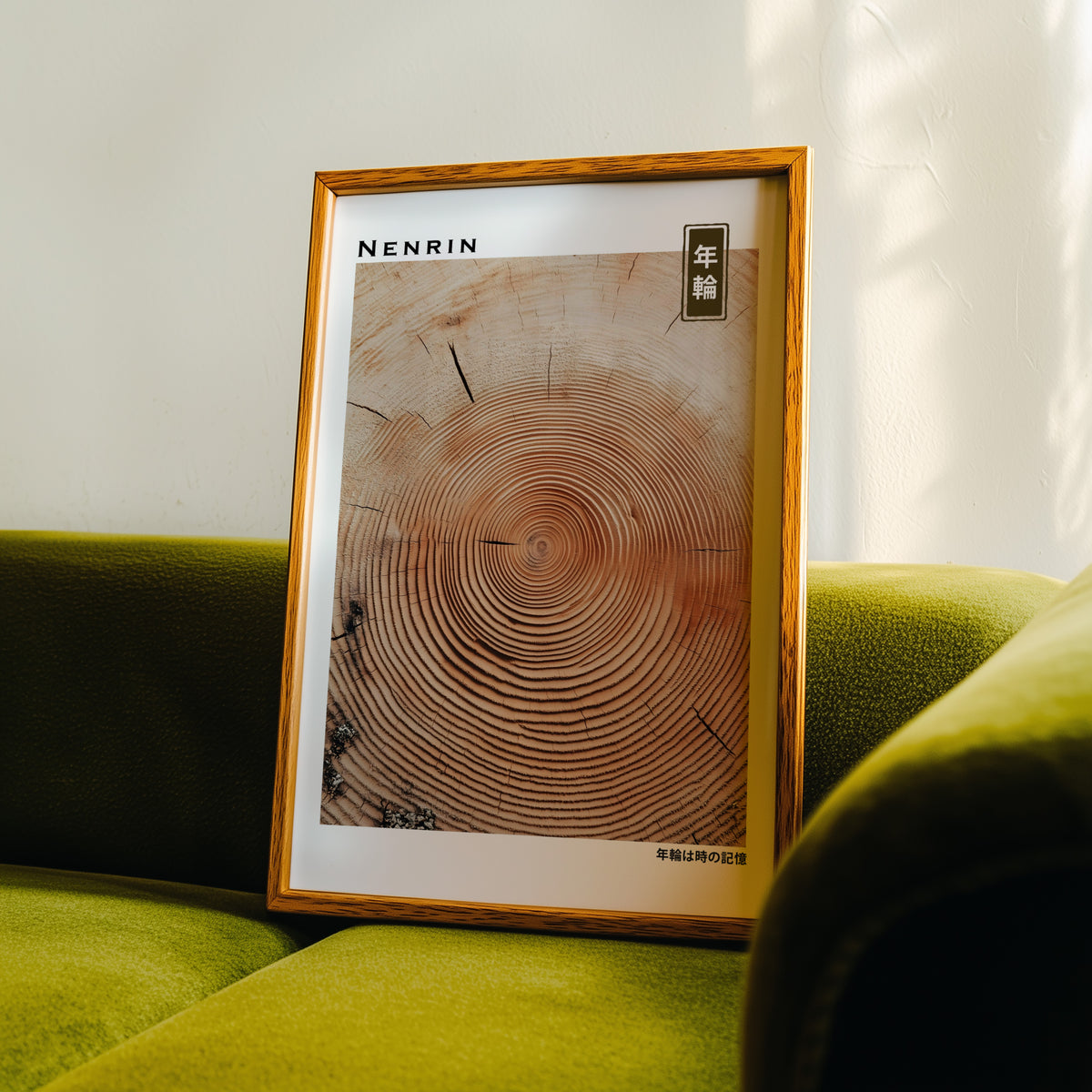 Orange-brown wood slice tree rings print in an oak frame propped on a green velvet sofa
