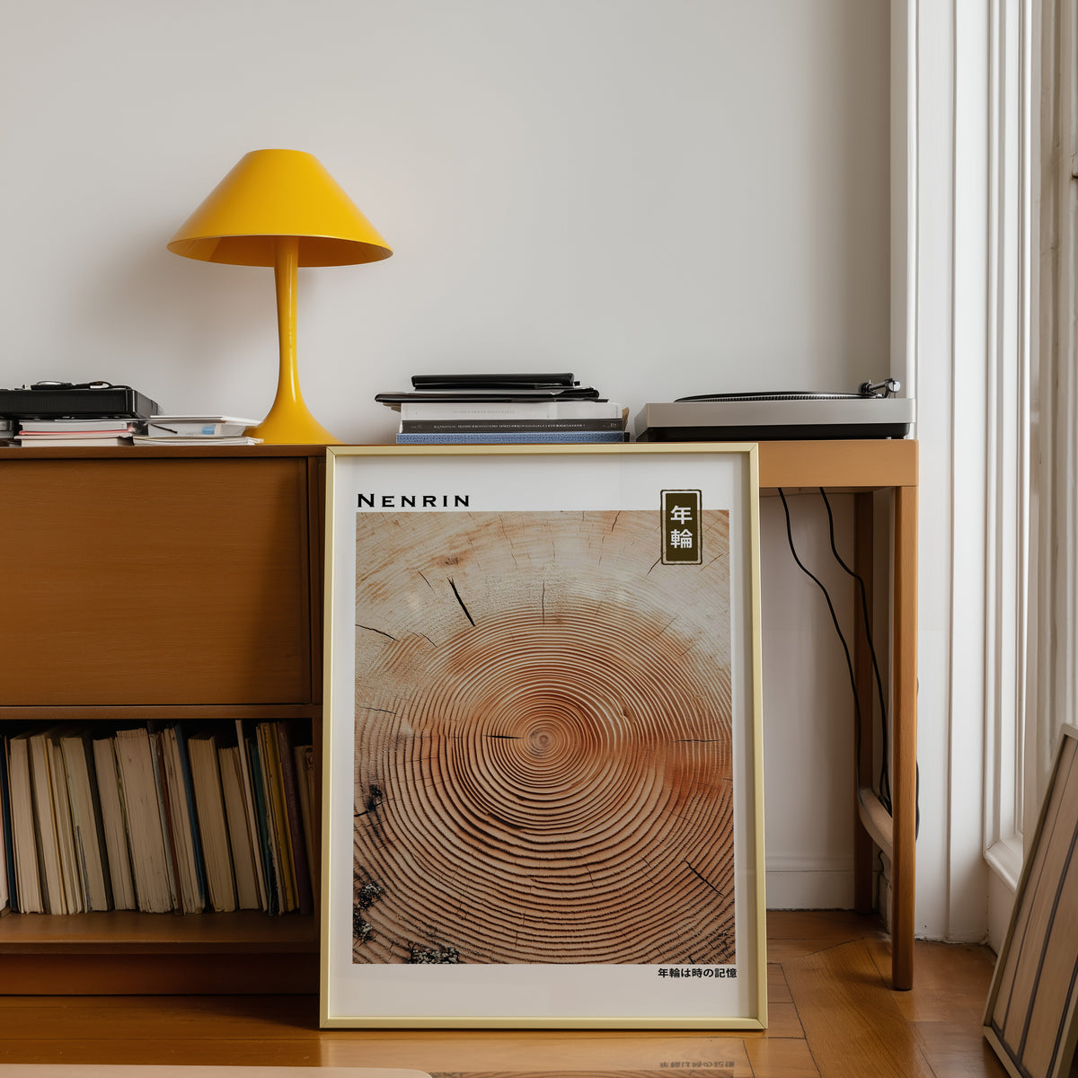 Orange-brown wood slice tree rings print shown in a gold frame below a teak desk with a yellow lamp