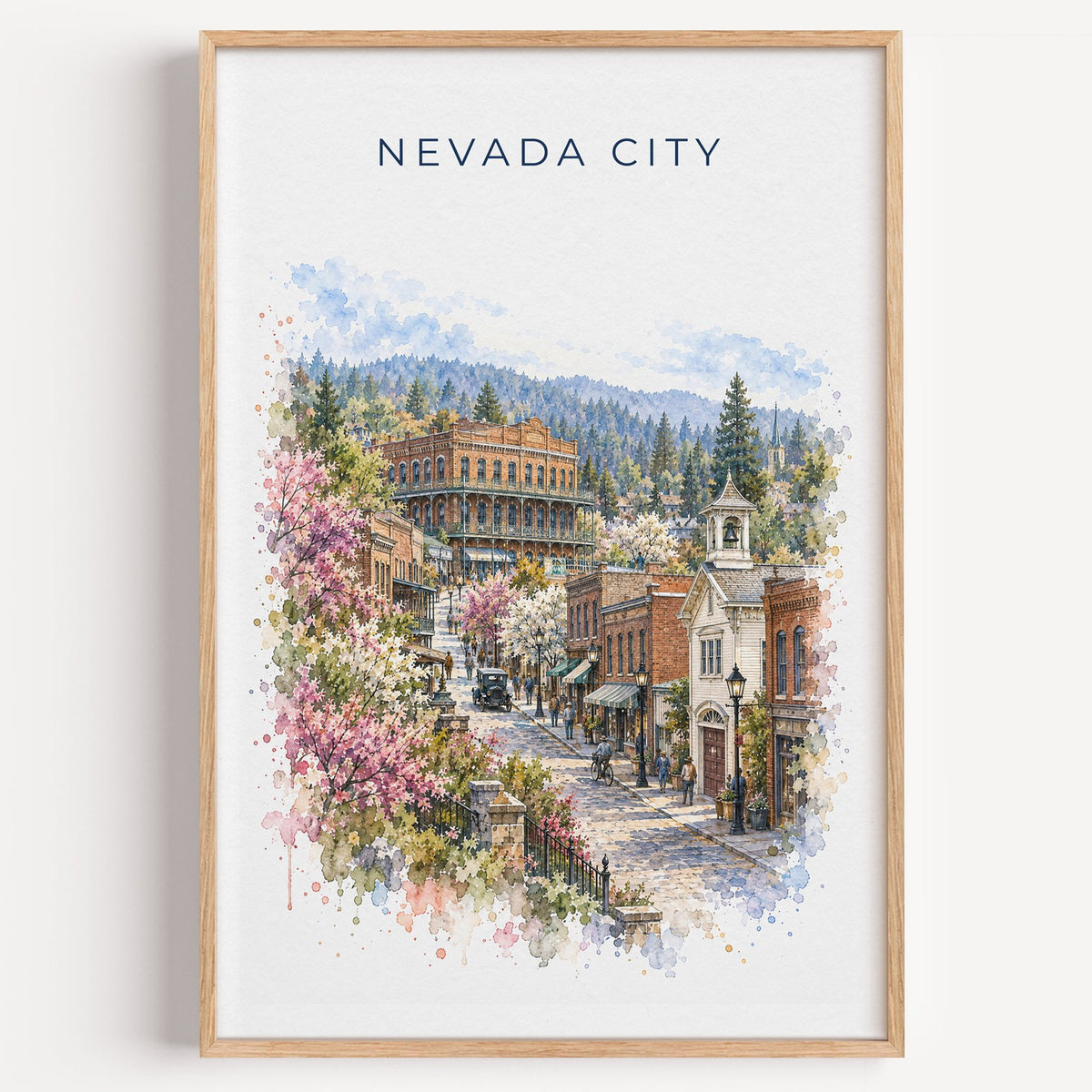 Nevada City, California watercolor print in a light oak frame on a plain white wall