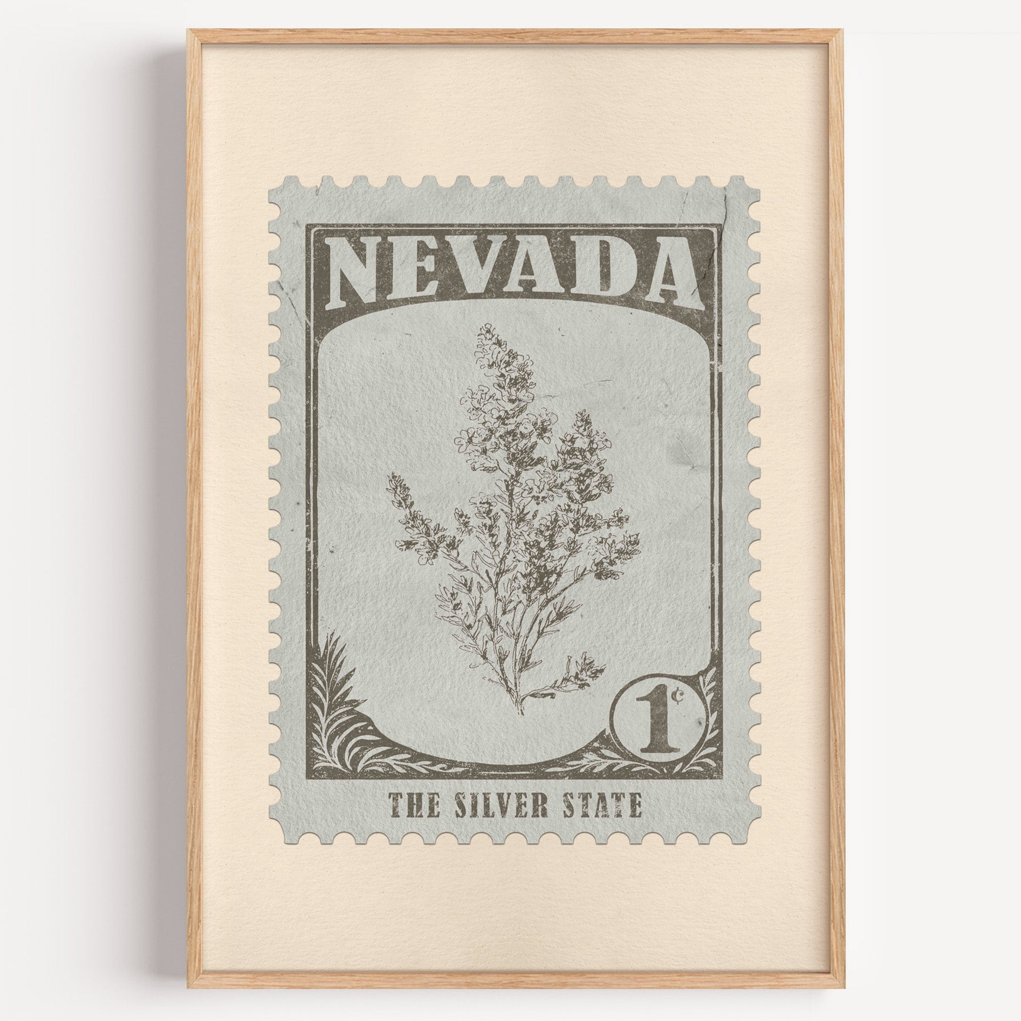 Nevada state flower stamp print in warm grey on pale grey-green, light oak frame on a plain white wall