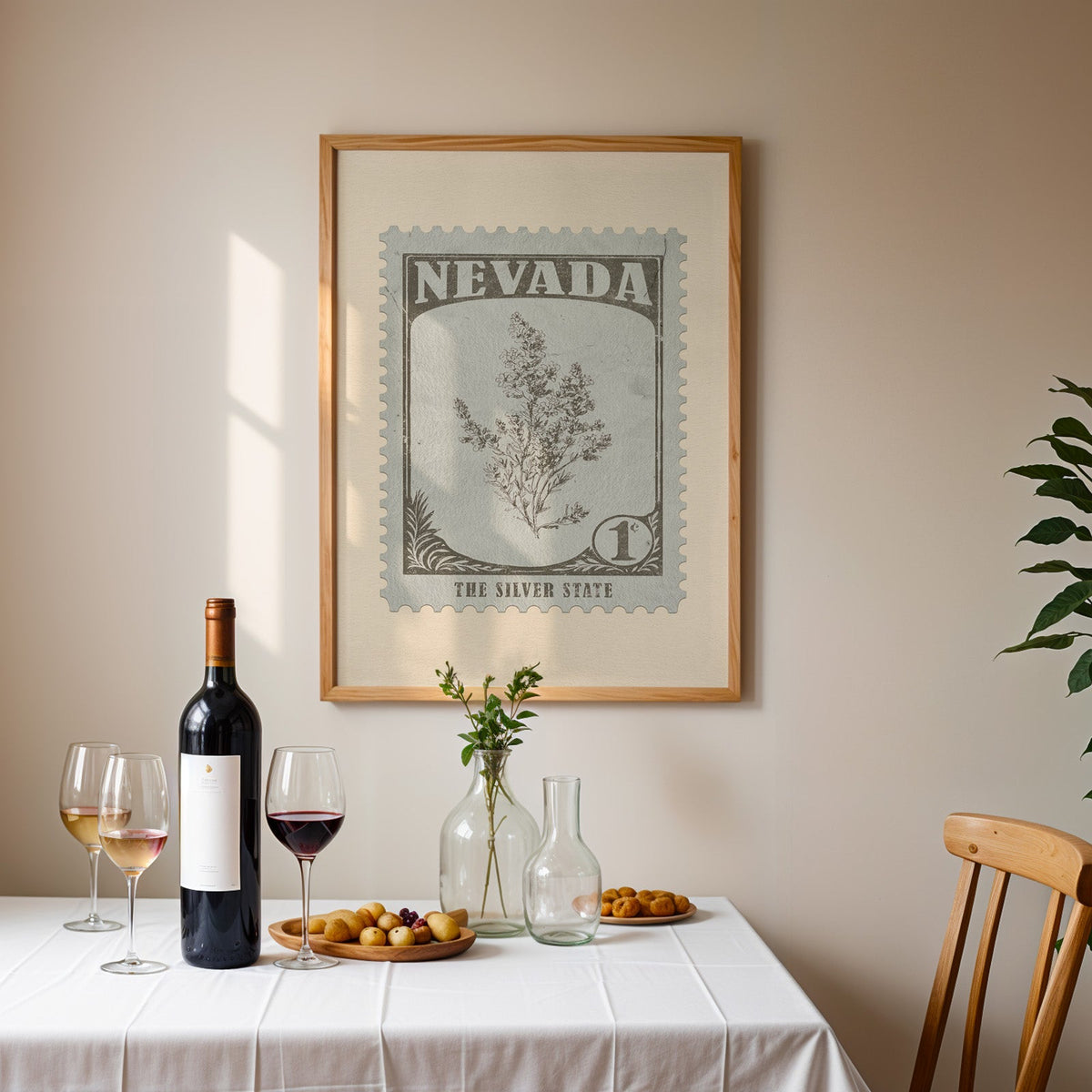 Nevada stamp print framed on the wall above a dining table set with wine, glasses and olives