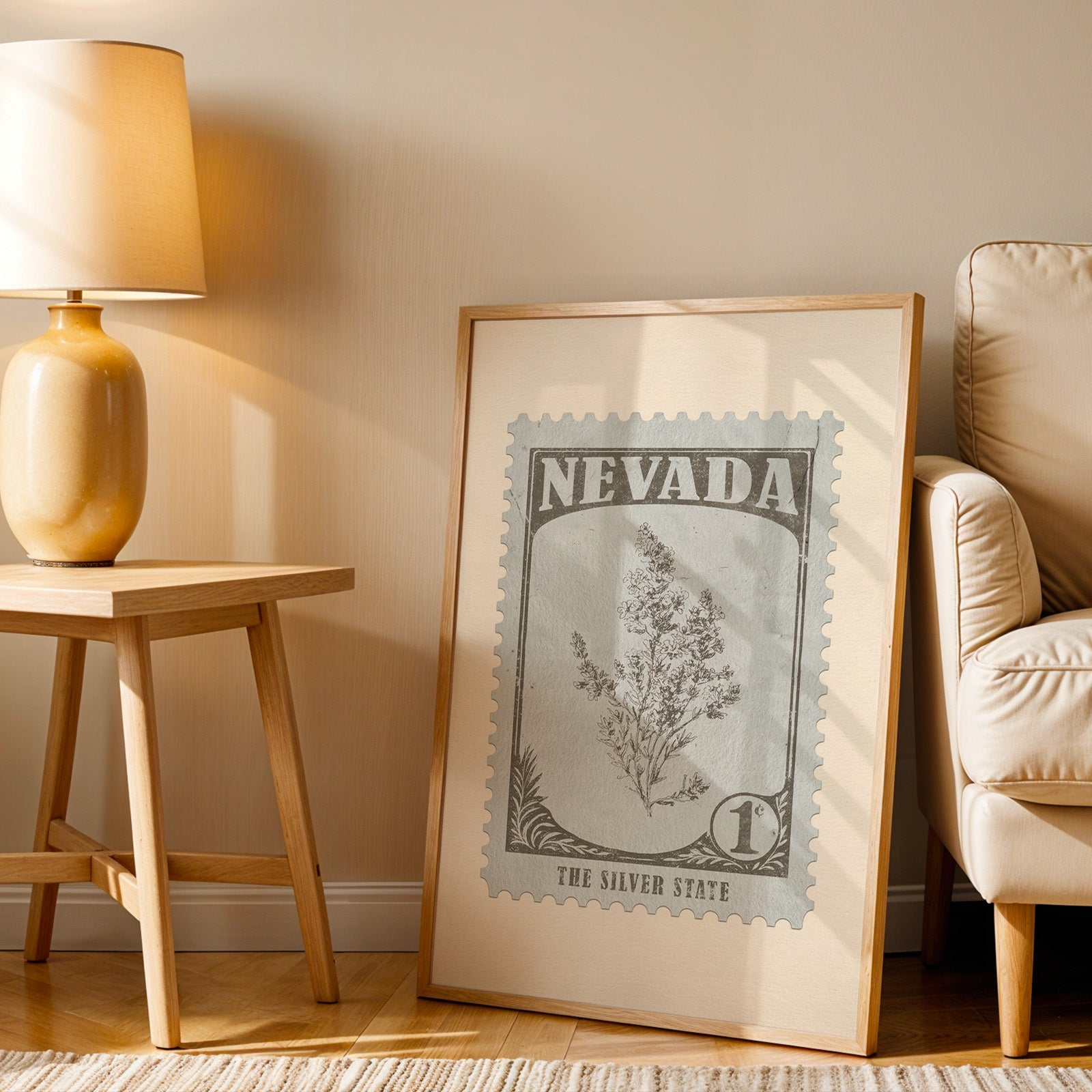 Nevada stamp print in a wood frame resting on the floor beside a beige armchair and a yellow lamp