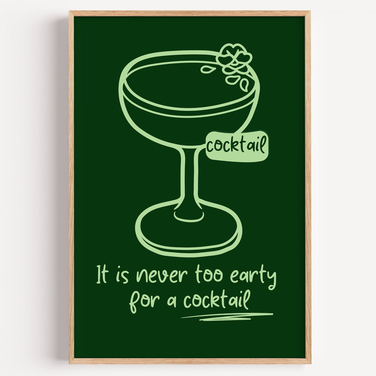 Never too early cocktail coupe print in a light oak frame on a plain white wall