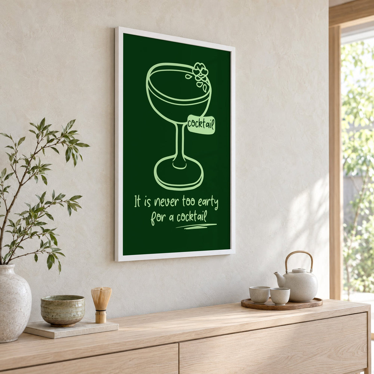 Never too early cocktail coupe print in a white frame above a pale wood console with a matcha tea set
