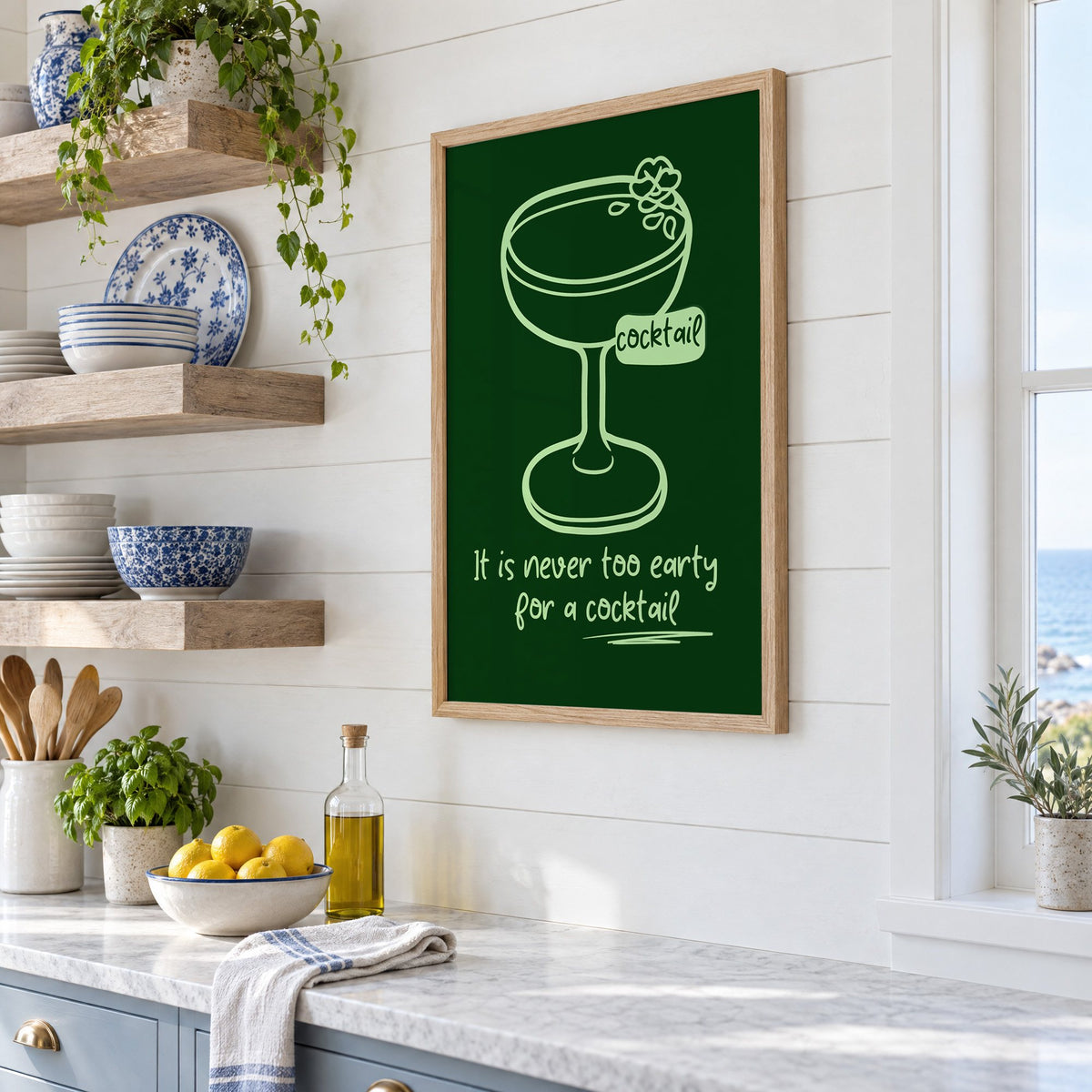 Never too early cocktail coupe print in an oak frame in a white coastal kitchen beside blue and white plates