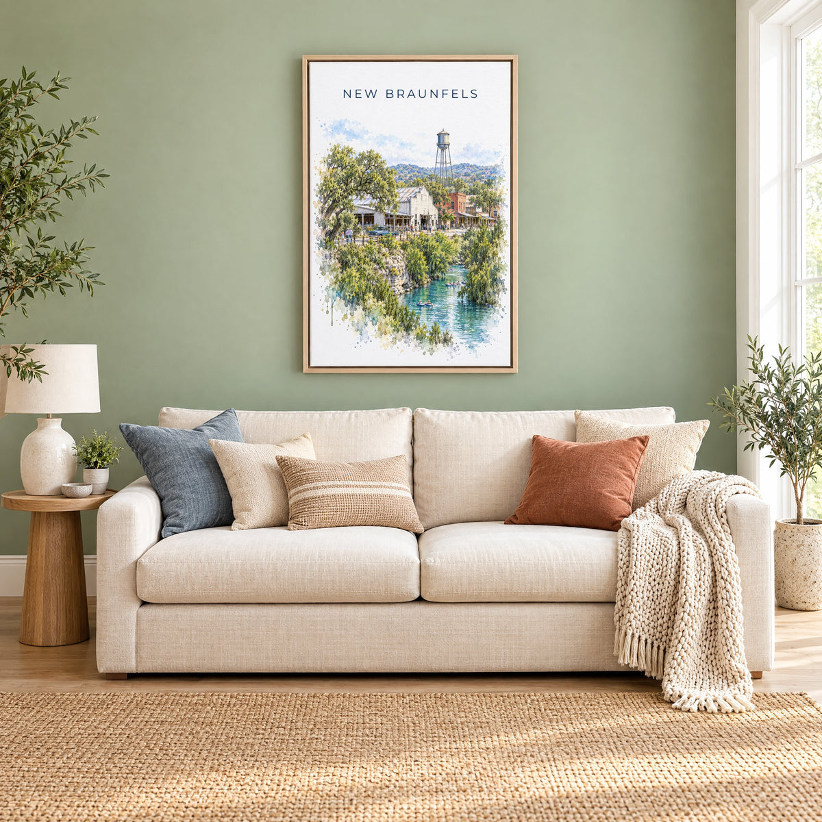 New Braunfels watercolor print as a natural floater canvas above a cream linen sofa on a sage green wall