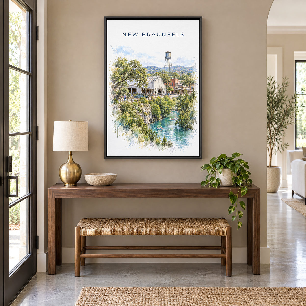 New Braunfels watercolor print as a black floater canvas above a walnut console and woven bench in an entryway