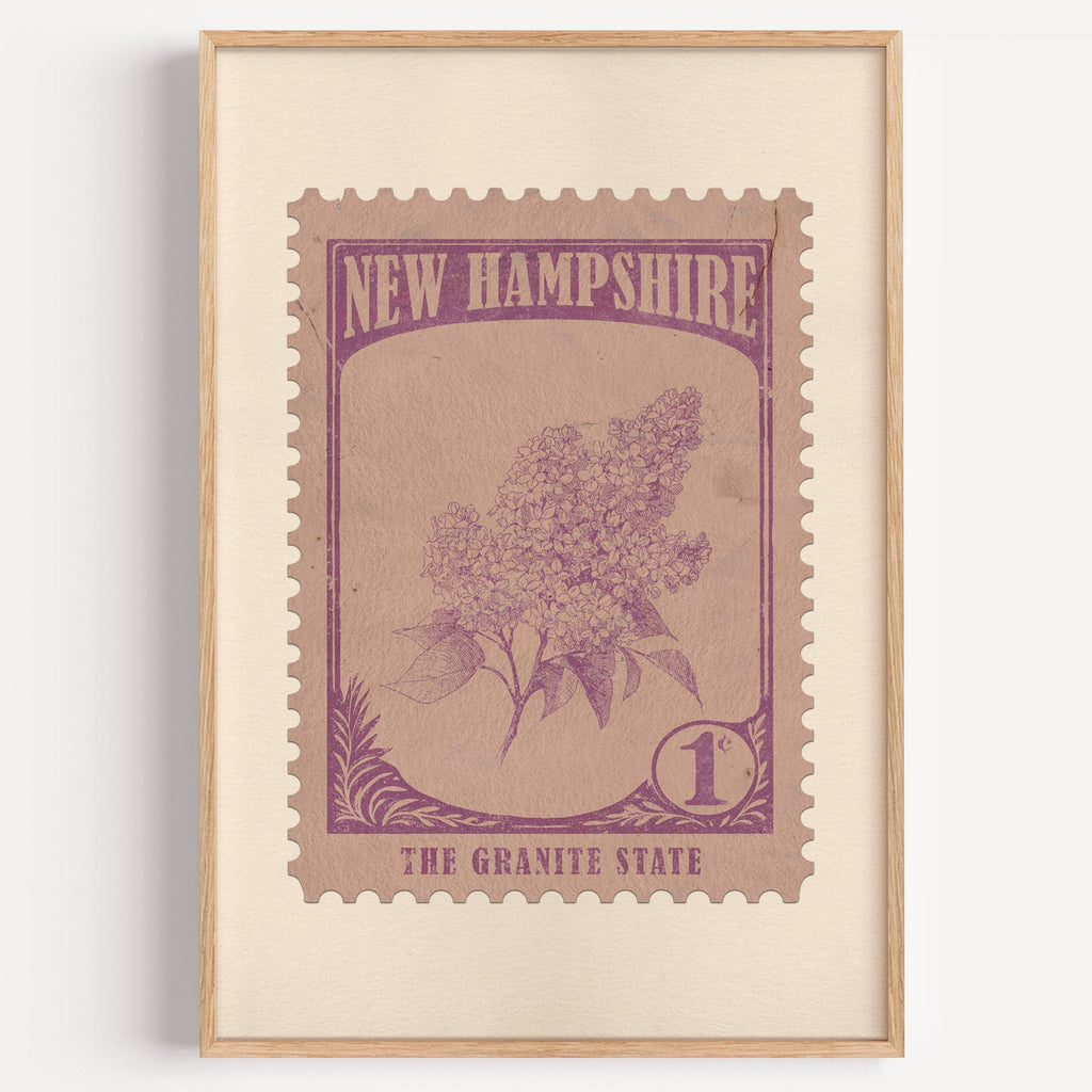 New Hampshire state flower stamp print in mauve purple on rose tan, light oak frame on a plain white wall