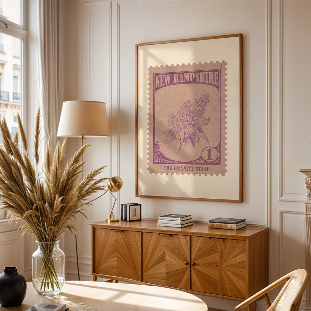 New Hampshire stamp print framed above a wooden sideboard, pampas grass in a glass vase and a floor lamp