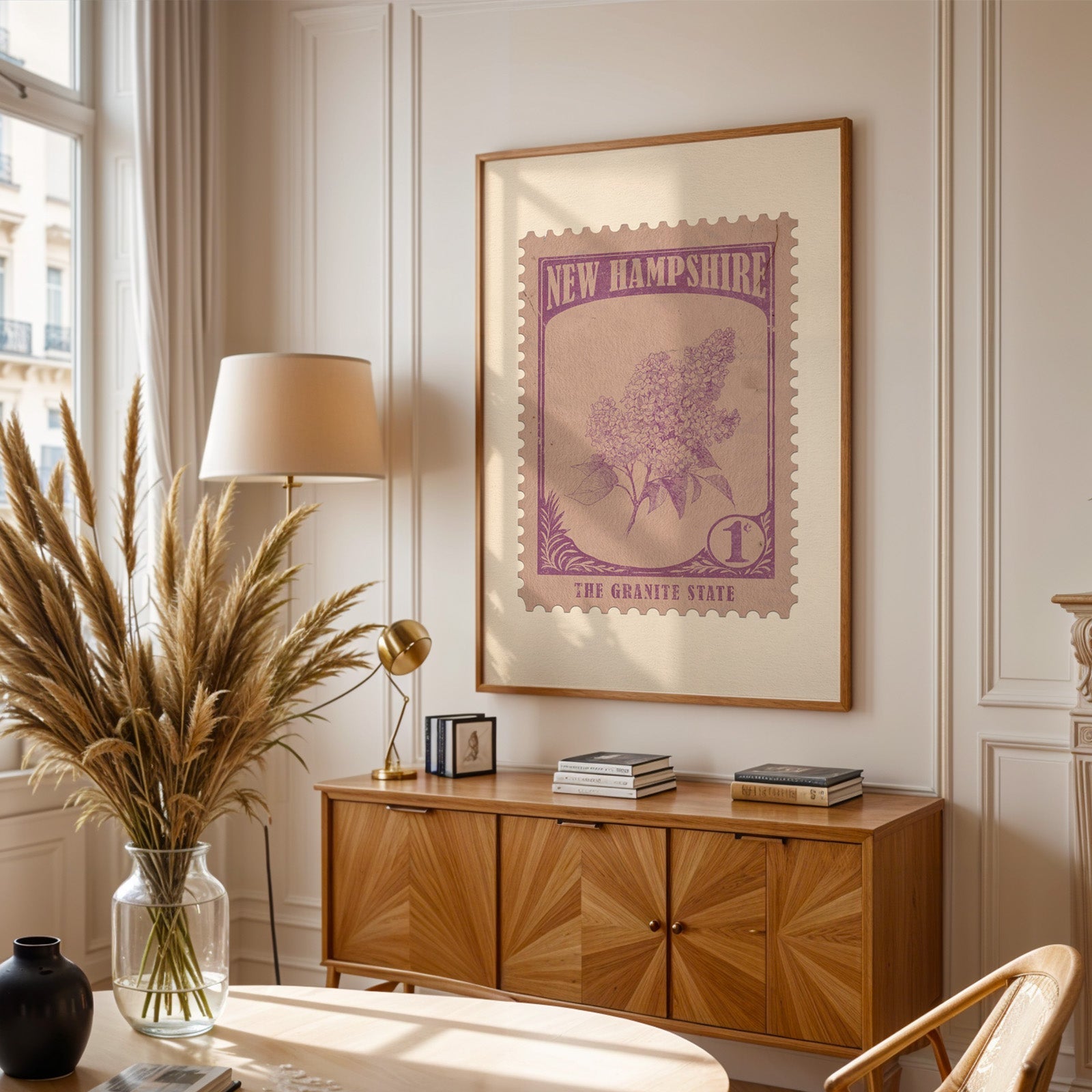 New Hampshire stamp print framed above a wooden sideboard, pampas grass in a glass vase and a floor lamp