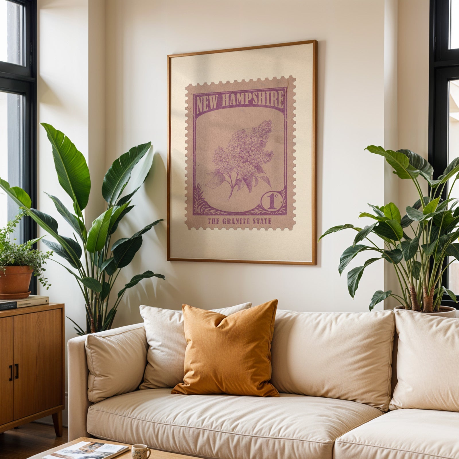 New Hampshire state flower print framed above a cream sofa with an ochre cushion and large plants either side