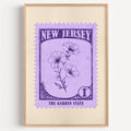 New Jersey state flower stamp print in deep violet on lavender, light oak frame on a plain white wall