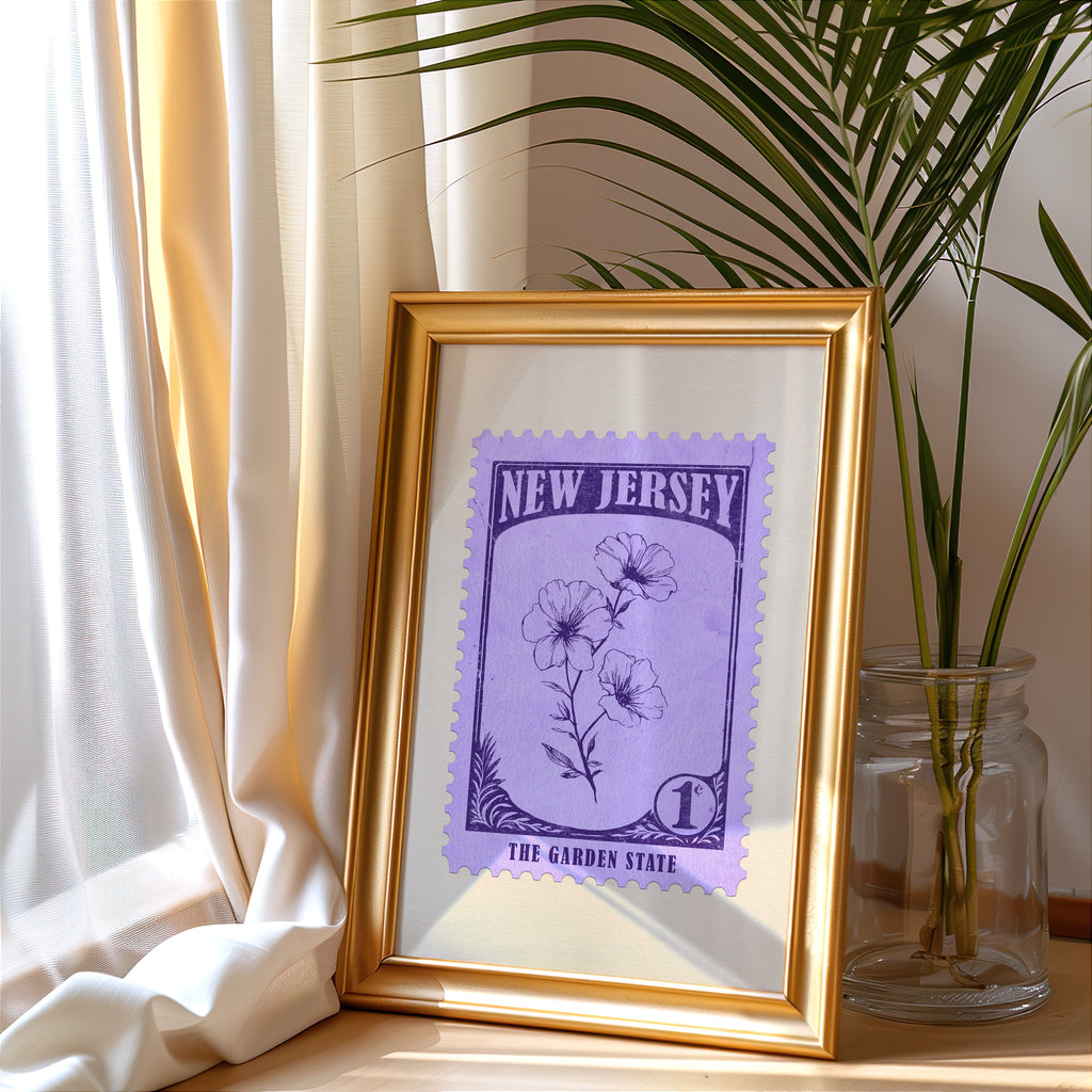 New Jersey stamp print in a gold frame leaning by a cream curtain with a palm in a glass jar