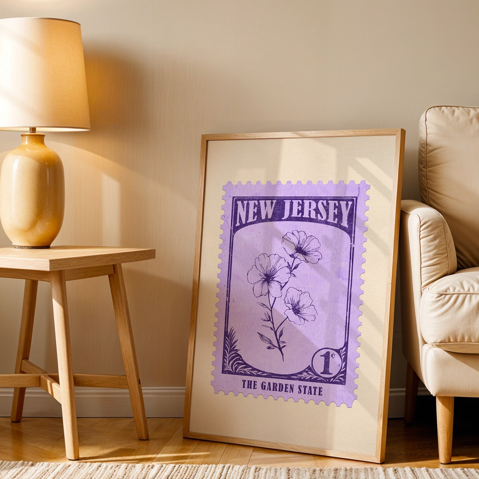 New Jersey stamp print in a wood frame resting on the floor beside a beige armchair and a yellow lamp