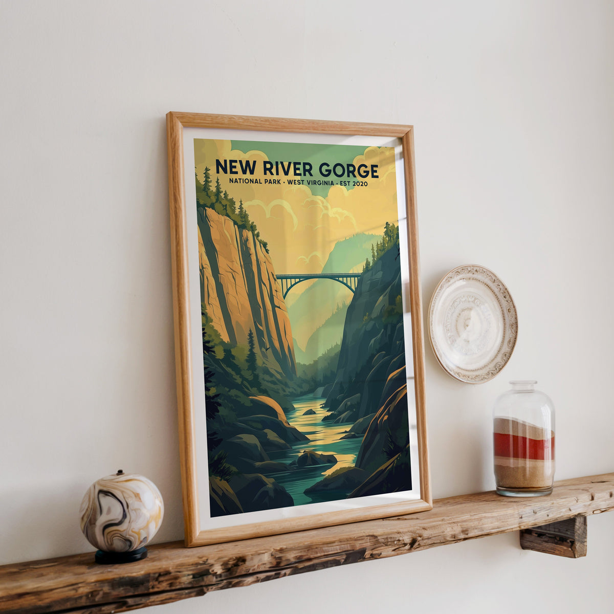 New River Gorge National Park print in an oak frame on a wood shelf with ceramics and a sand-filled jar