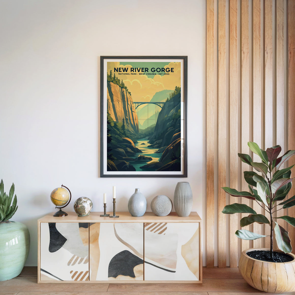 New River Gorge National Park print in a black frame above a light wood sideboard with a globe and ceramic vases