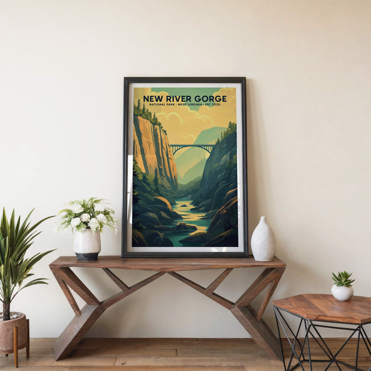 New River Gorge poster in a black frame on an entryway console table beside white flowers and a yucca
