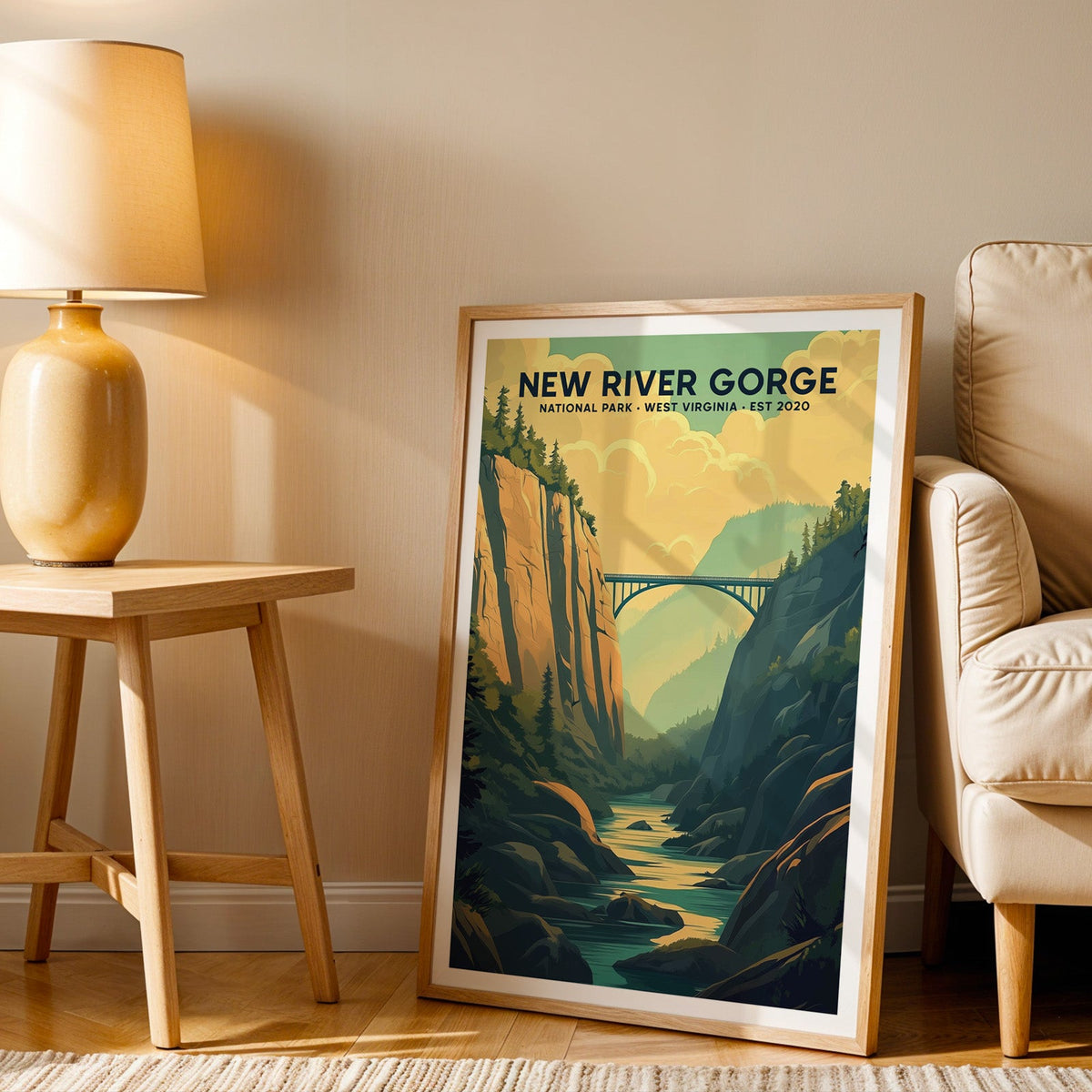 New River Gorge print in an oak frame beside a cream armchair and an amber lamp in warm afternoon light