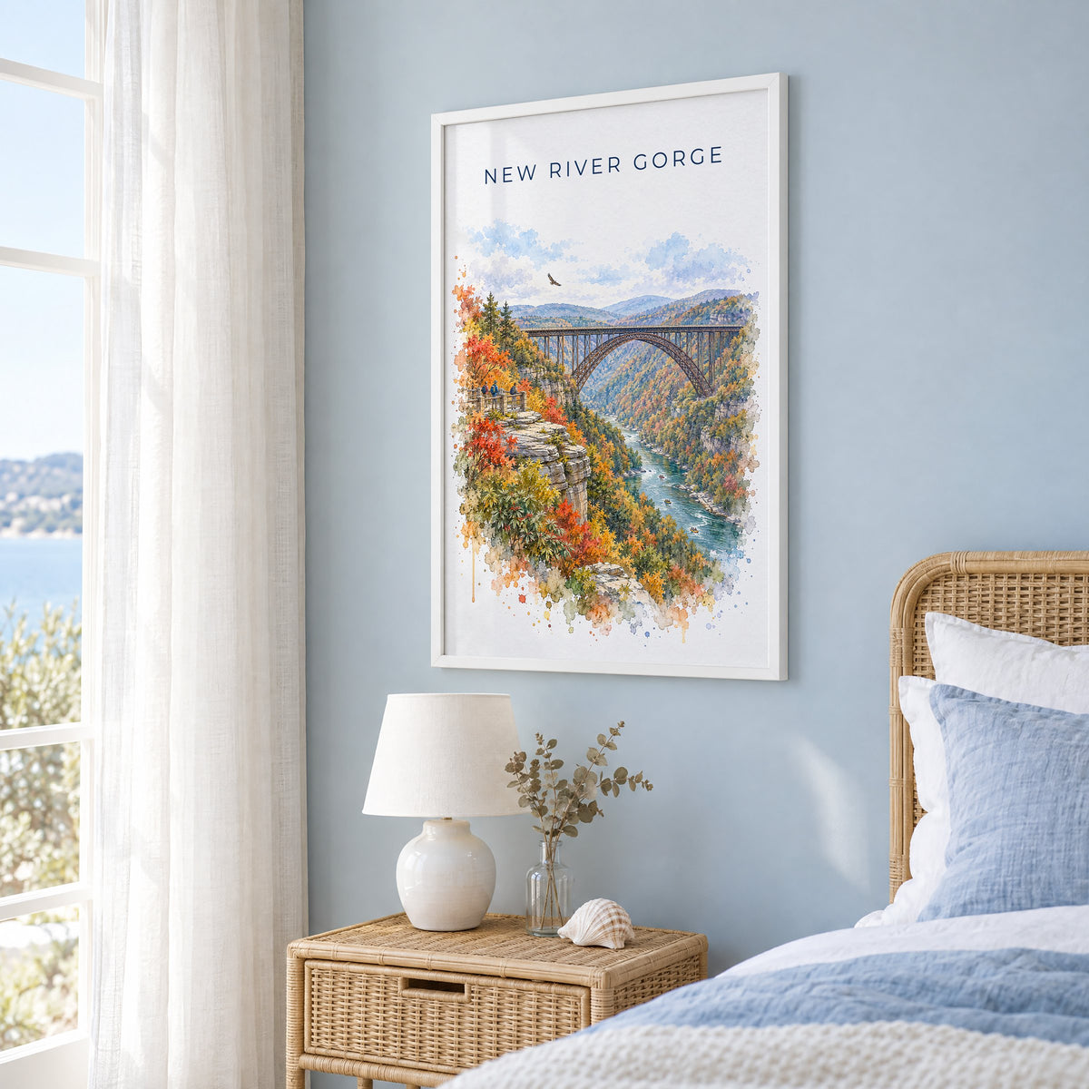 New River Gorge National Park watercolor print in a white frame on a pale blue wall beside a rattan bed in a coastal bedroom