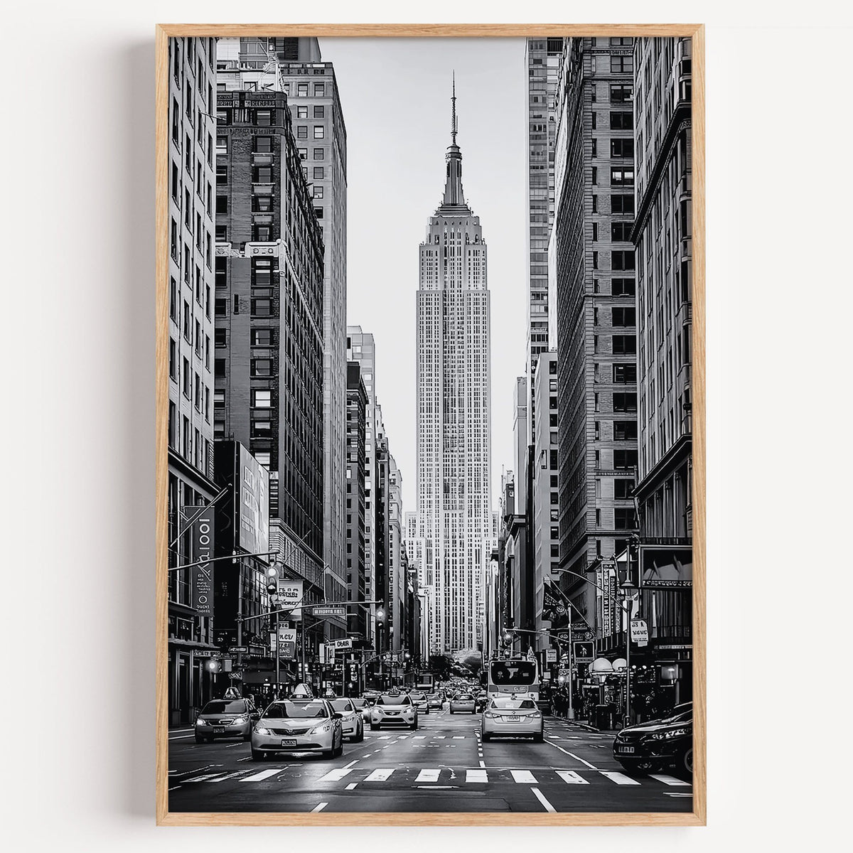 Empire State Building avenue with taxis print in a light oak frame on a plain white wall