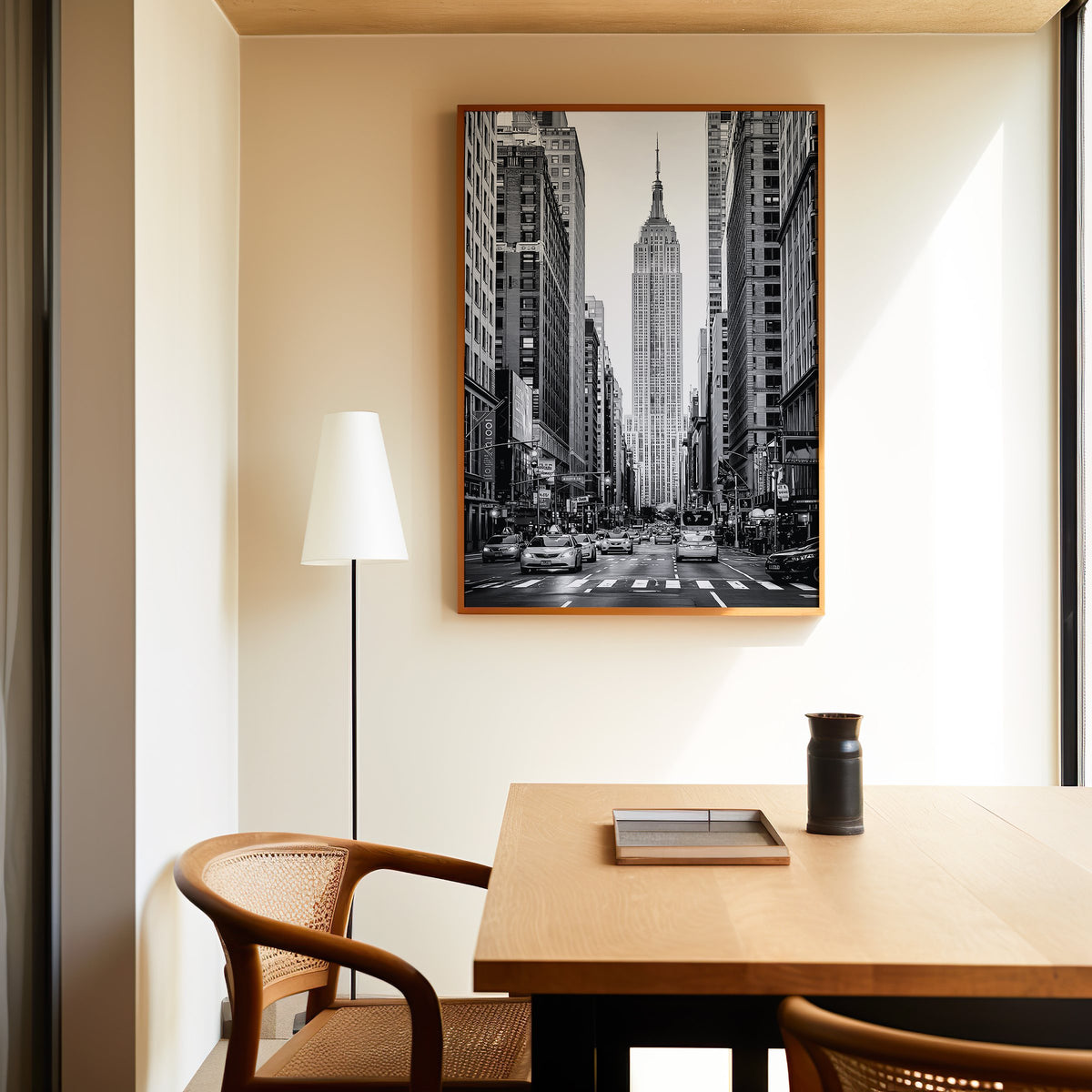 Empire State Building avenue with taxis print in an oak frame above a dining table and cane chair