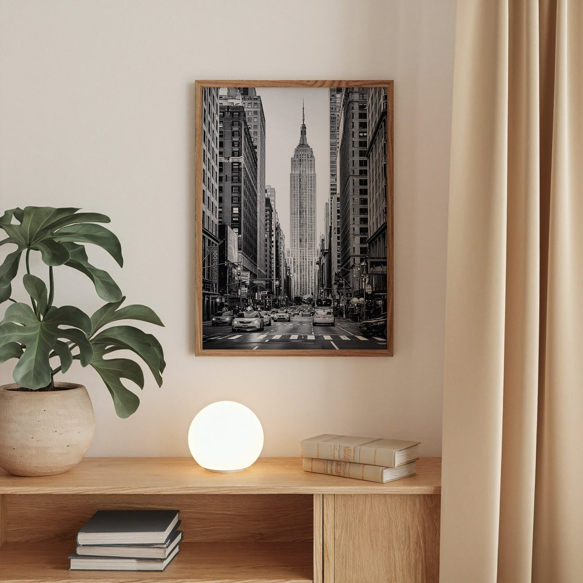 Empire State Building avenue with taxis print in a walnut frame above an oak cabinet with a glowing globe lamp