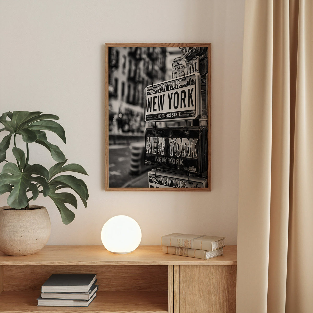 New York souvenir license plates on a rack print in a walnut frame above an oak cabinet with a glowing globe lamp