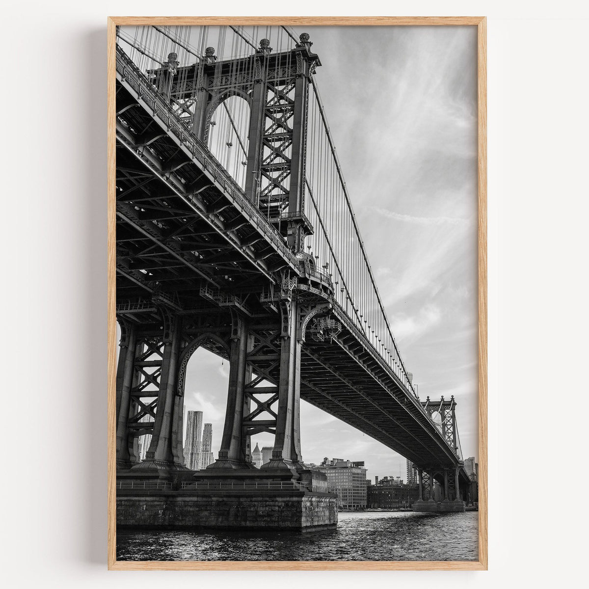 Manhattan Bridge underside from the river print in a light oak frame on a plain white wall
