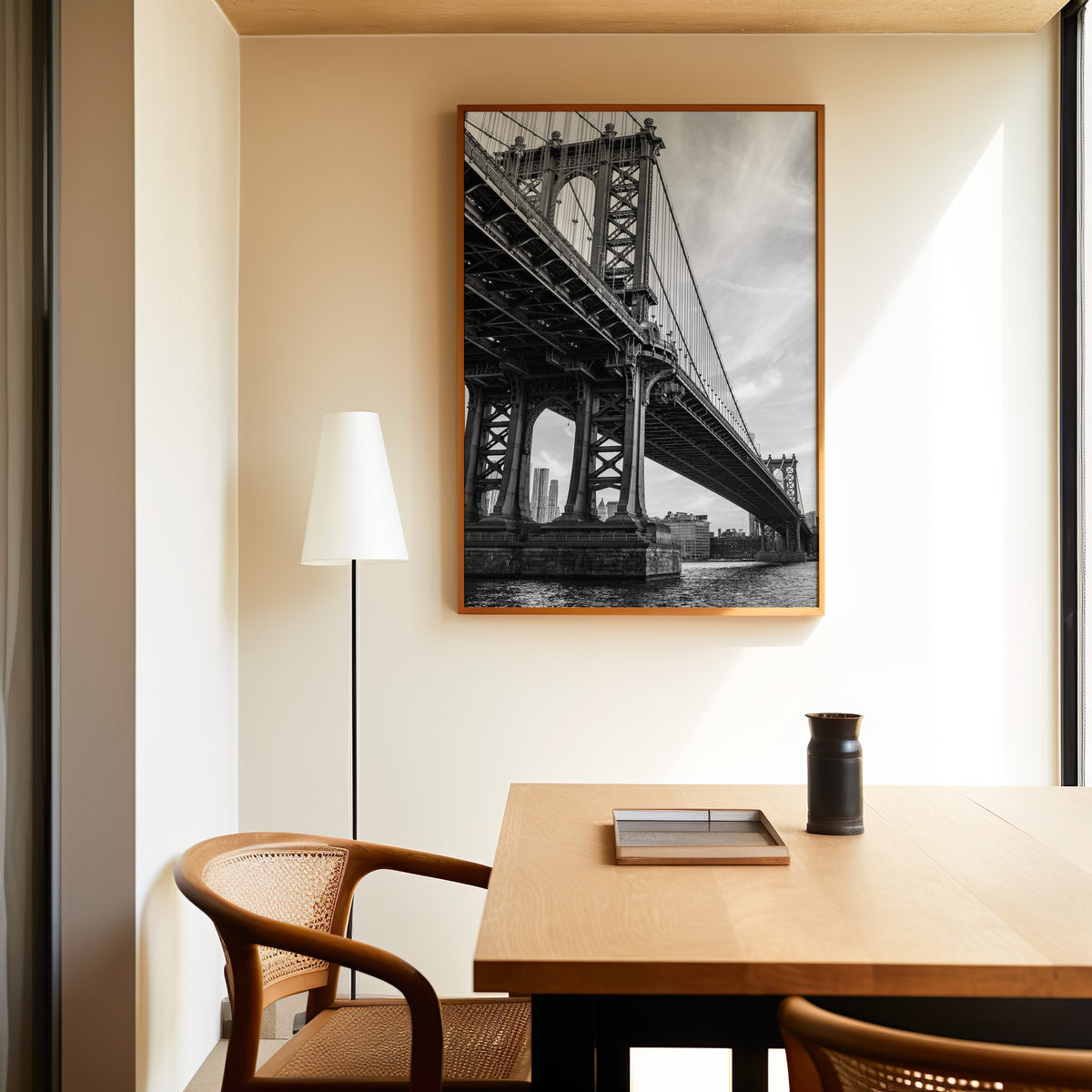 Manhattan Bridge underside from the river print in an oak frame above a dining table and cane chair