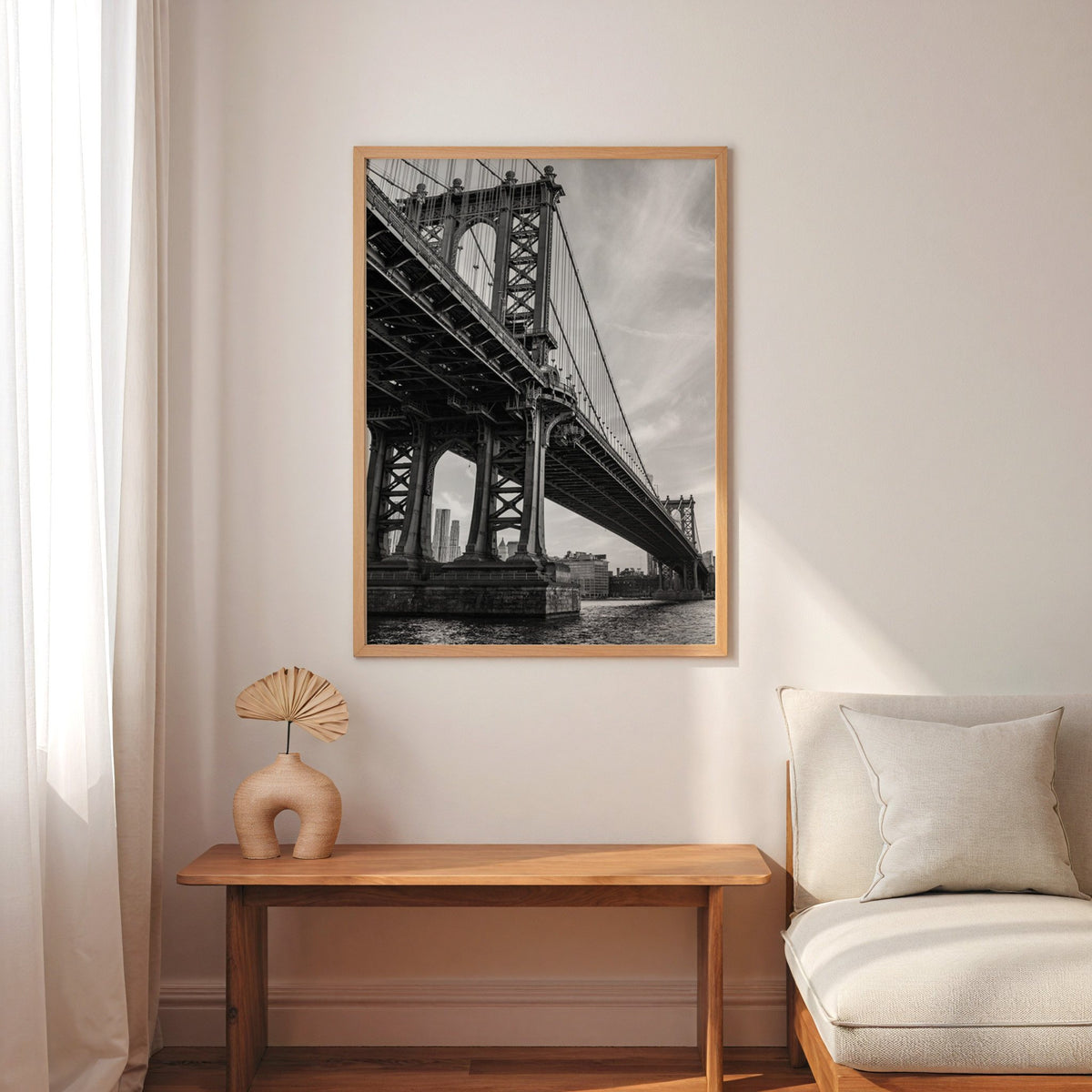 Manhattan Bridge underside from the river print in an oak frame above a narrow console with an arched vase