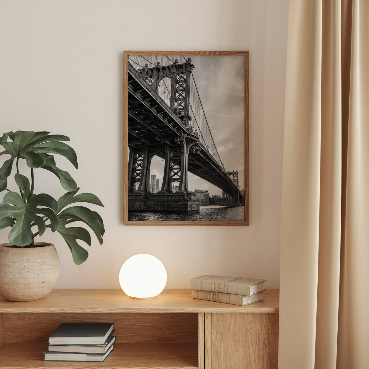 Manhattan Bridge underside from the river print in a walnut frame above an oak cabinet with a glowing globe lamp