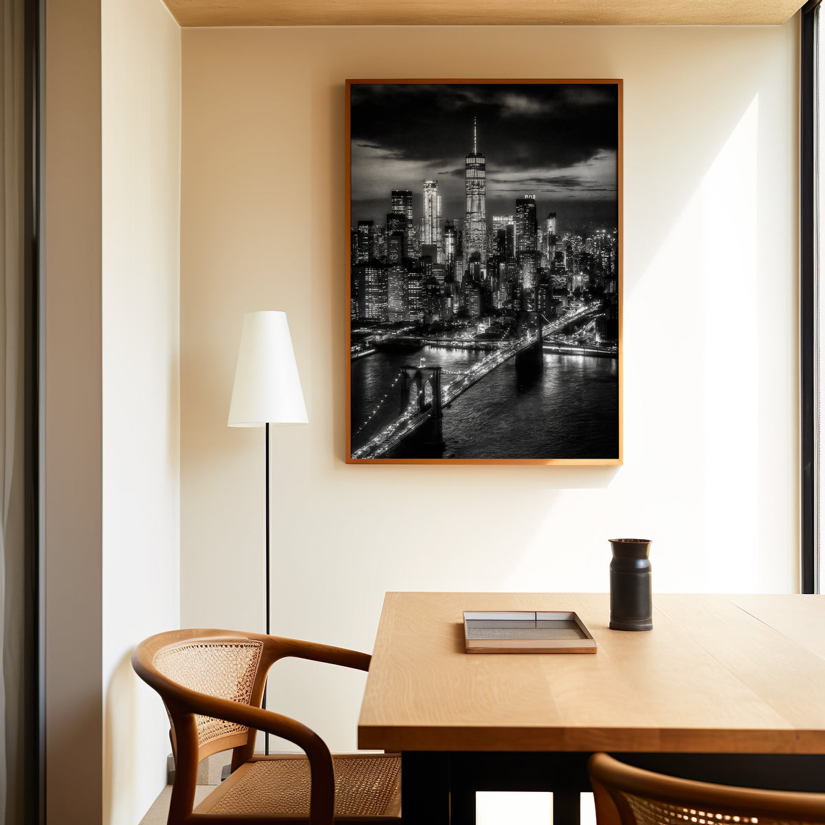 New York skyline at night with Brooklyn Bridge print in an oak frame above a dining table and cane chair
