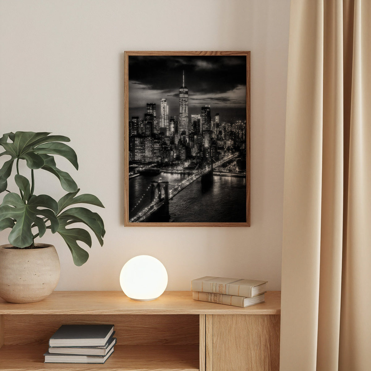 New York skyline at night with Brooklyn Bridge print in a walnut frame above an oak cabinet with a glowing globe lamp