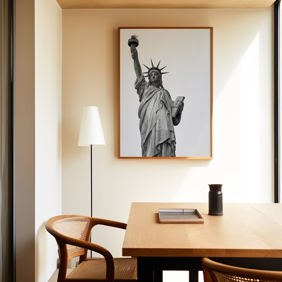 Statue of Liberty torch and tablet photo print in an oak frame above a dining table and cane chair