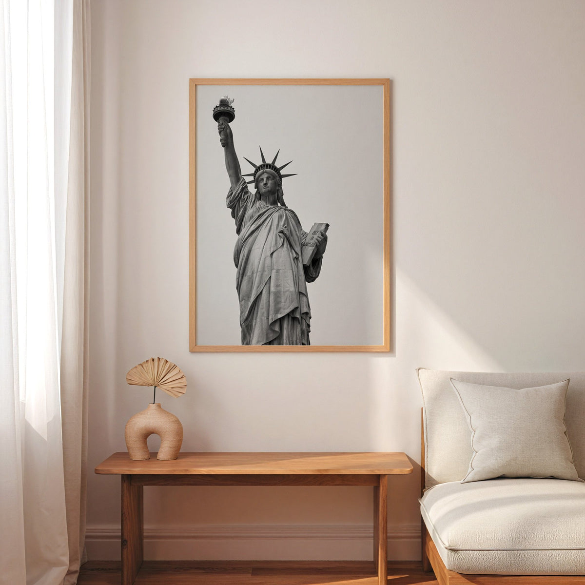 Statue of Liberty torch and tablet photo print in an oak frame above a narrow console with an arched vase