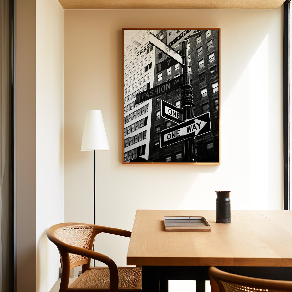 New York street sign pole with one way signs print in an oak frame above a dining table and cane chair
