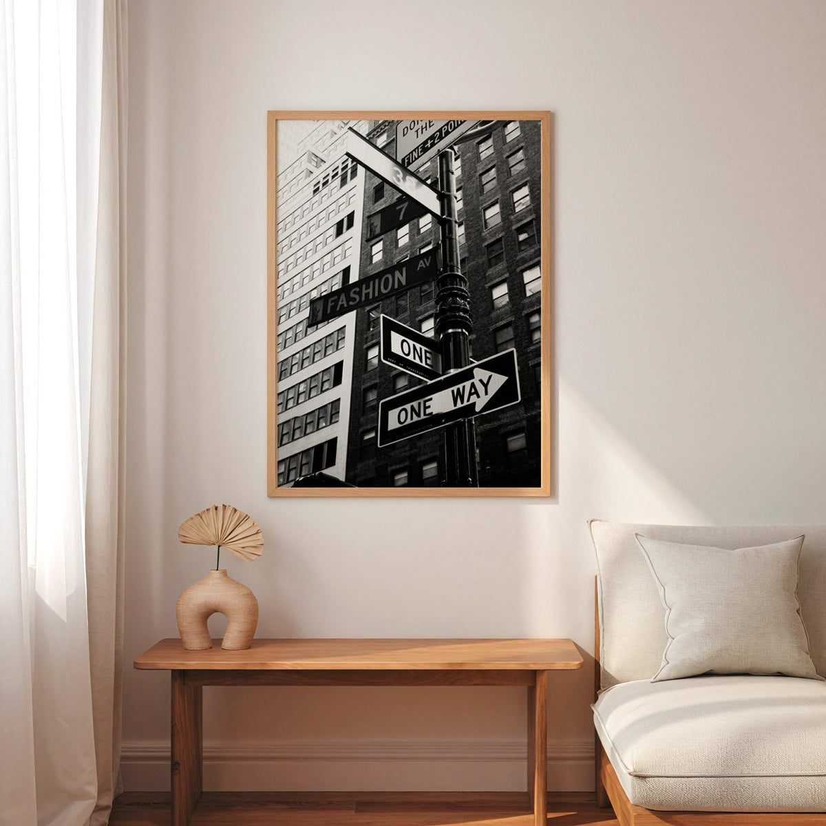New York street sign pole with one way signs print in an oak frame above a narrow console with an arched vase