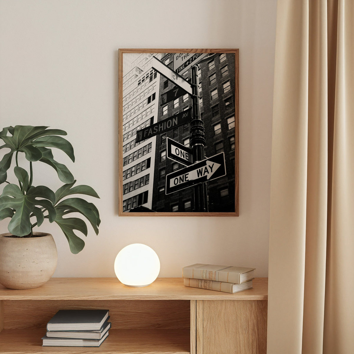New York street sign pole with one way signs print in a walnut frame above an oak cabinet with a glowing globe lamp