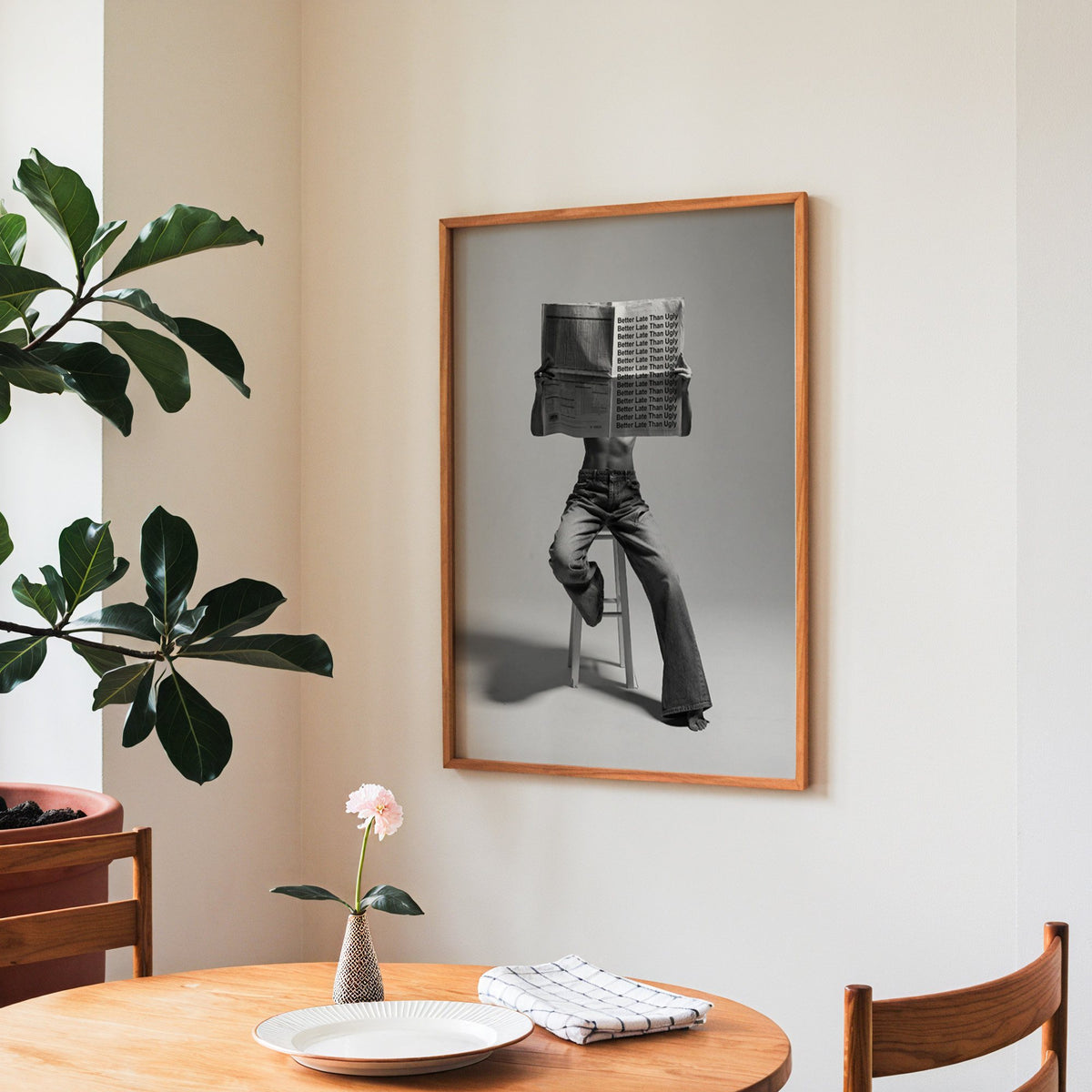 Figure on stool behind newspaper with repeated quote print in a teak frame above a round wooden dining table
