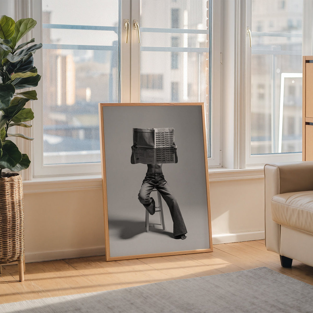 Figure on stool behind newspaper with repeated quote print in an oak frame leaning on the floor beside a fiddle leaf fig