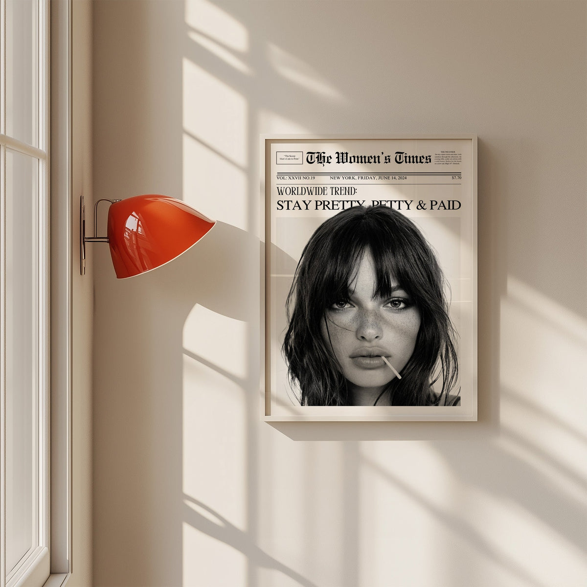 Mock front page with close-up of woman and lollipop print in a white frame on a sunlit wall beside a red sconce