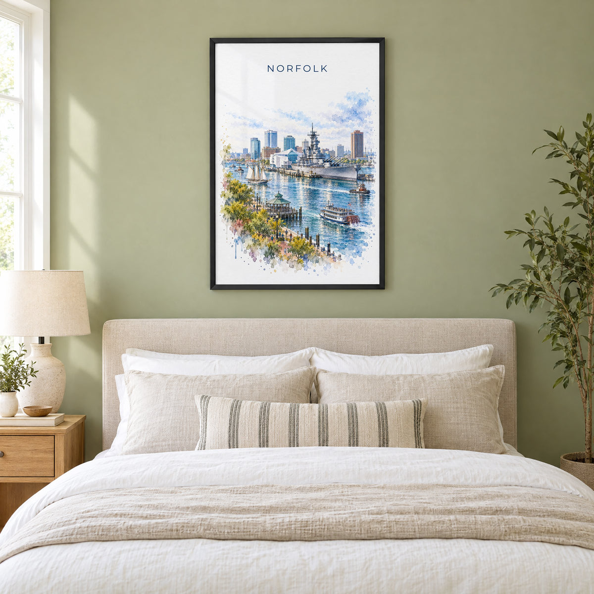 Norfolk, Virginia watercolor print in a black frame above an upholstered headboard in a sage green bedroom