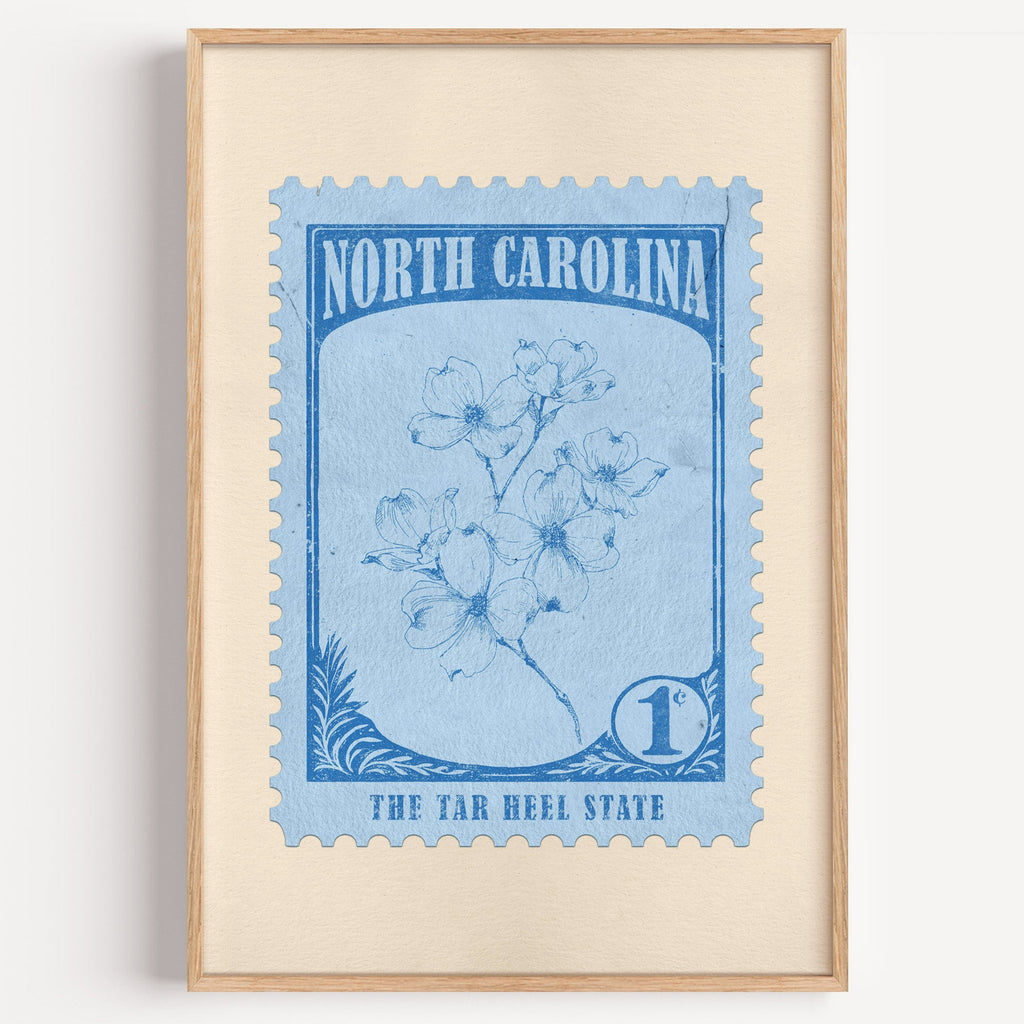North Carolina state flower stamp print in mid blue on sky, light oak frame on a plain white wall