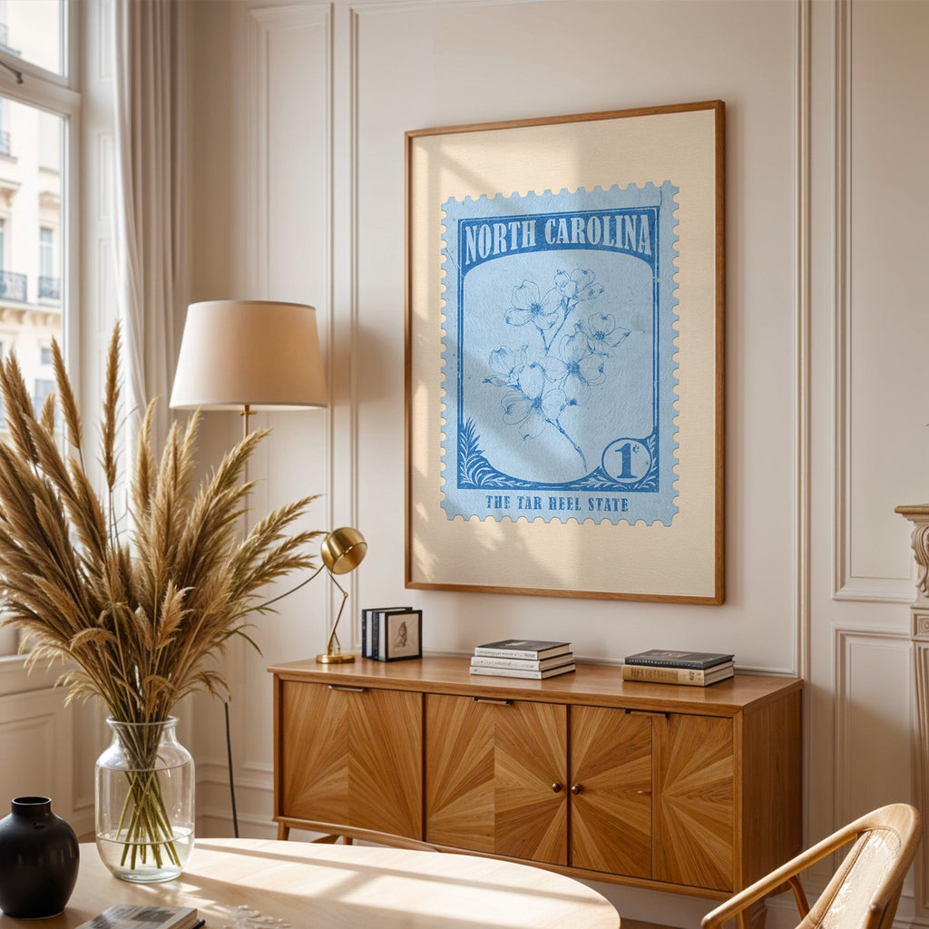 North Carolina stamp print framed above a wooden sideboard, pampas grass in a glass vase and a floor lamp
