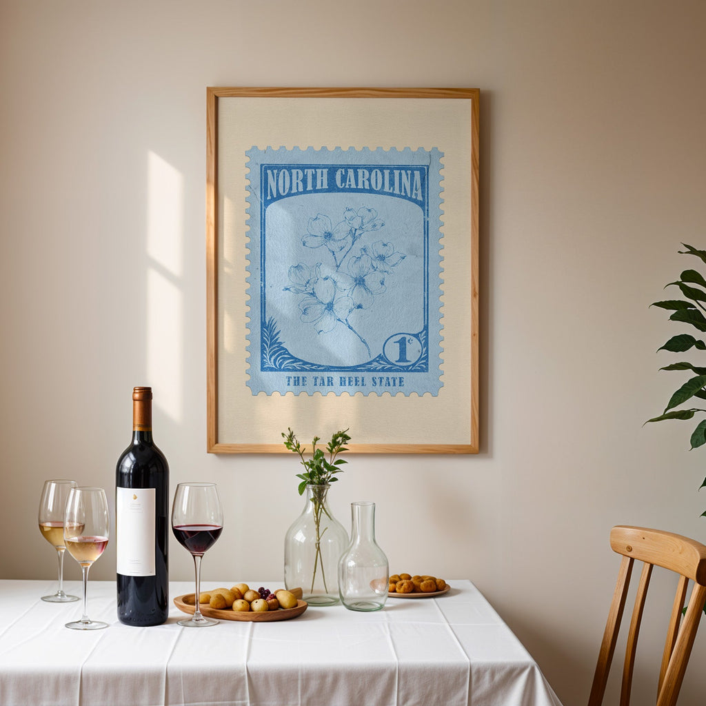 North Carolina stamp print framed on the wall above a dining table set with wine, glasses and olives