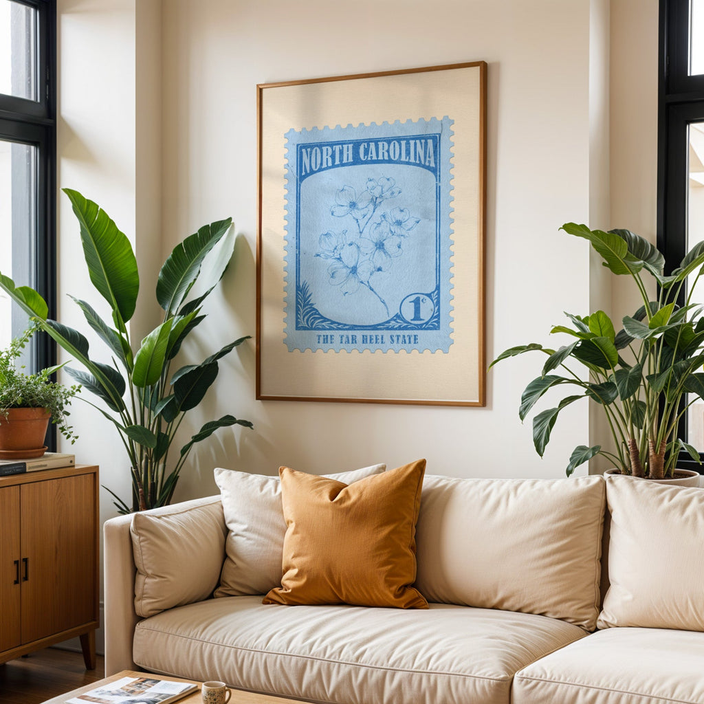 North Carolina state flower print framed above a cream sofa with an ochre cushion and large plants either side