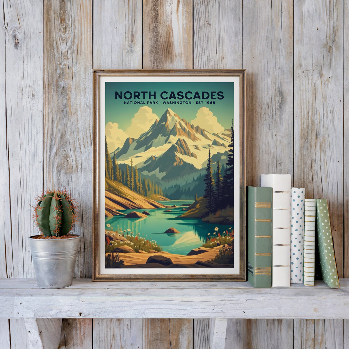 North Cascades poster in an antique gold frame against whitewashed planks beside books and a cactus