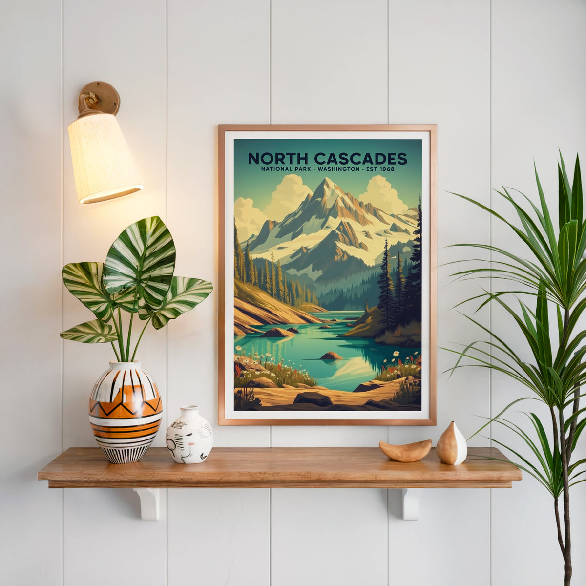 North Cascades National Park print in a copper frame above an oak shelf on white shiplap with a brass sconce
